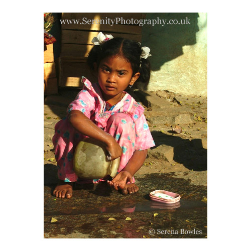 Small girl washes her hands at the side of the road. Hampi, India.